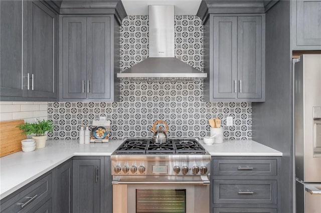 kitchen with tasteful backsplash, gray cabinetry, stainless steel appliances, and wall chimney range hood