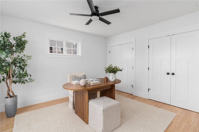 home office with light hardwood / wood-style floors and ceiling fan