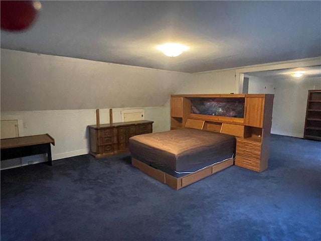 bedroom with dark colored carpet and lofted ceiling