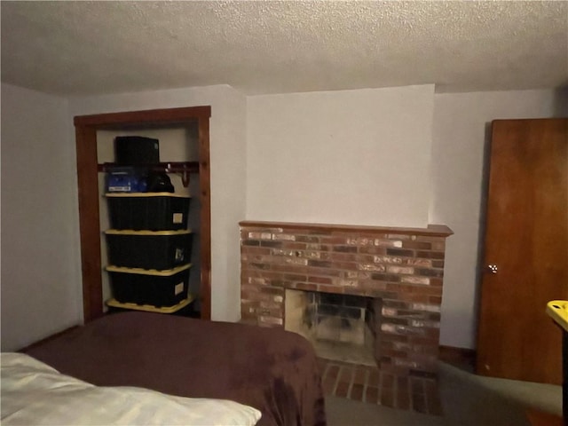 bedroom with a textured ceiling and a brick fireplace