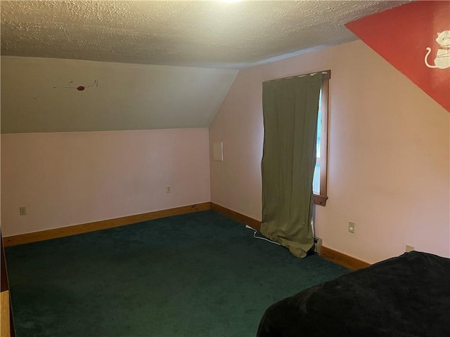 additional living space with lofted ceiling, a textured ceiling, and dark colored carpet