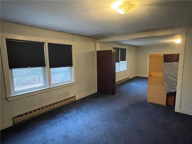 spare room featuring dark colored carpet and a baseboard heating unit