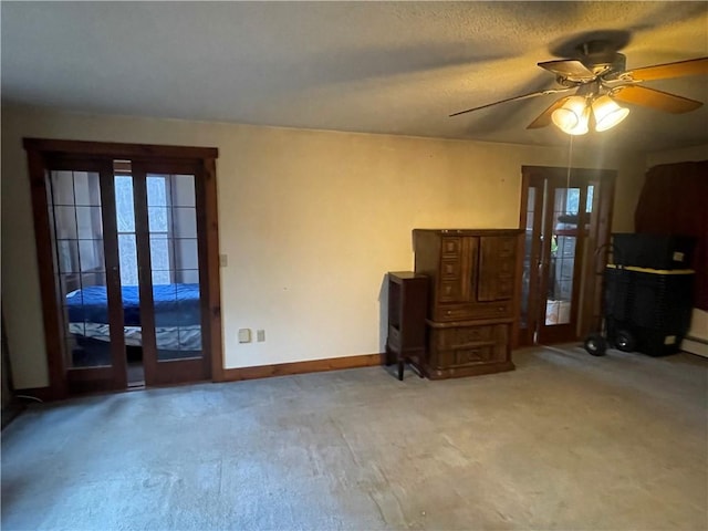 unfurnished living room with a textured ceiling, ceiling fan, and light carpet