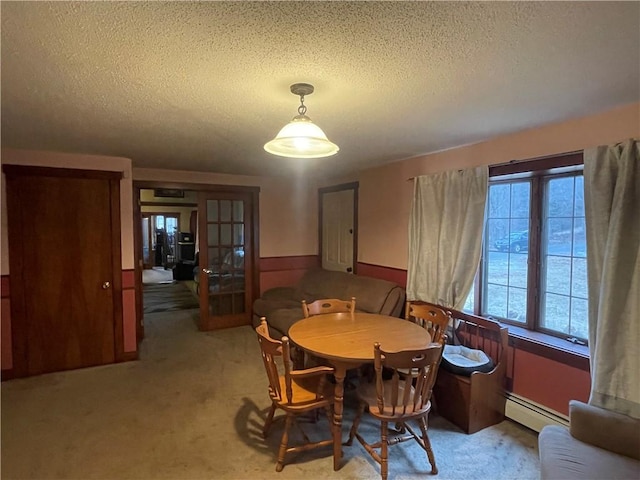 carpeted dining area with a textured ceiling and a baseboard heating unit