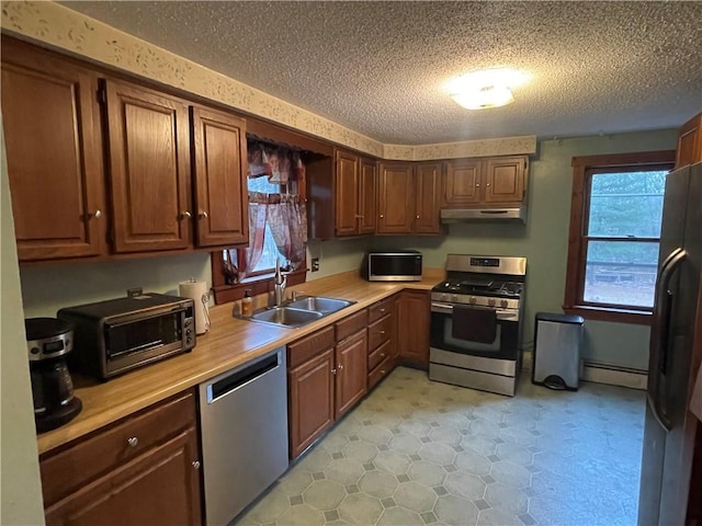 kitchen featuring sink, a baseboard radiator, a textured ceiling, and appliances with stainless steel finishes