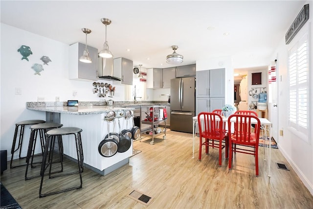 kitchen with pendant lighting, a healthy amount of sunlight, gray cabinetry, and stainless steel refrigerator