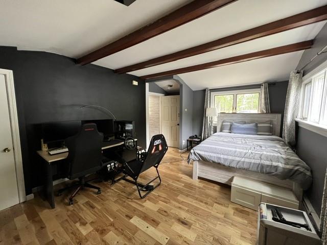 bedroom featuring lofted ceiling with beams and light hardwood / wood-style floors