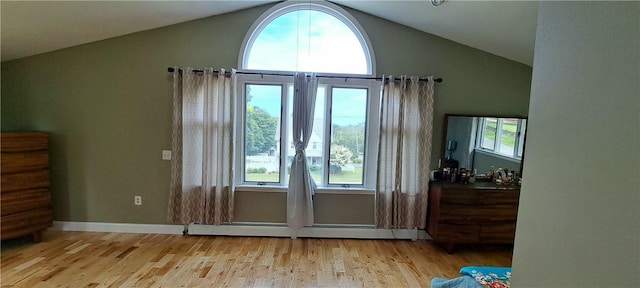 doorway to outside with light hardwood / wood-style floors, a baseboard radiator, a wealth of natural light, and vaulted ceiling