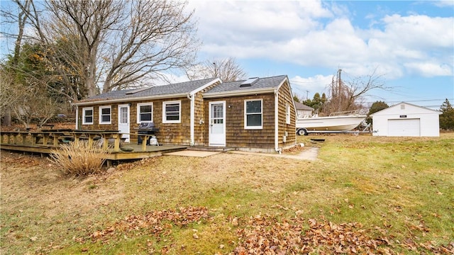 back of property with a lawn, a garage, an outdoor structure, and a wooden deck