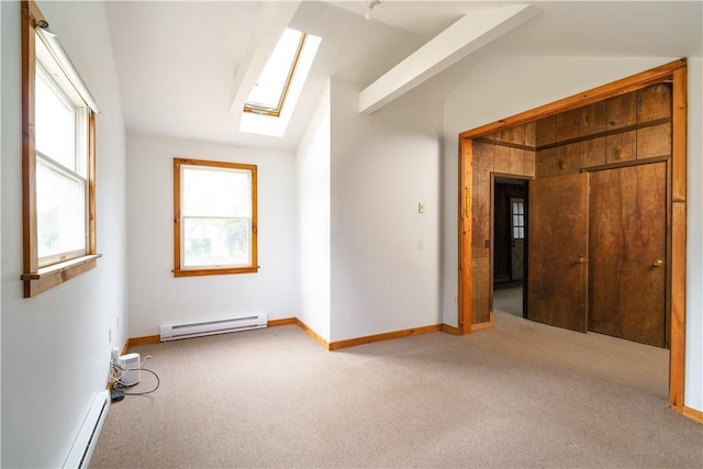 unfurnished room with lofted ceiling with skylight, plenty of natural light, a baseboard radiator, and light carpet