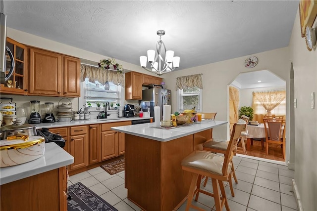 kitchen with light tile patterned floors, a center island, decorative light fixtures, and stainless steel refrigerator