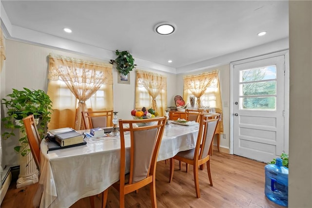 dining space with baseboard heating and light hardwood / wood-style flooring