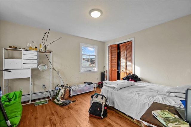 bedroom with hardwood / wood-style flooring, a closet, and a baseboard radiator