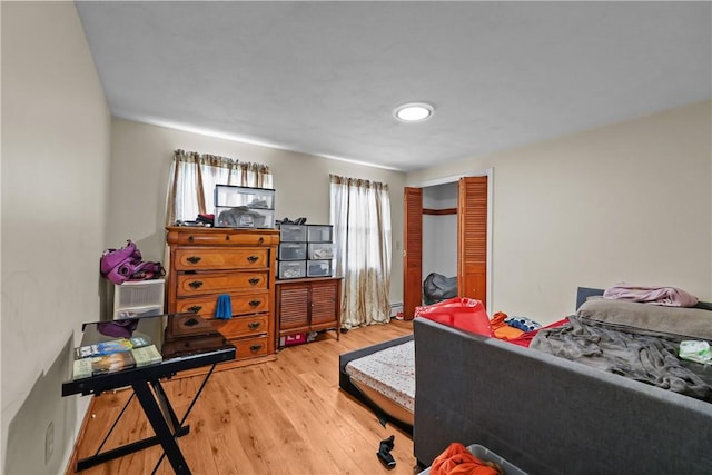 bedroom featuring multiple windows, wood-type flooring, and a baseboard radiator