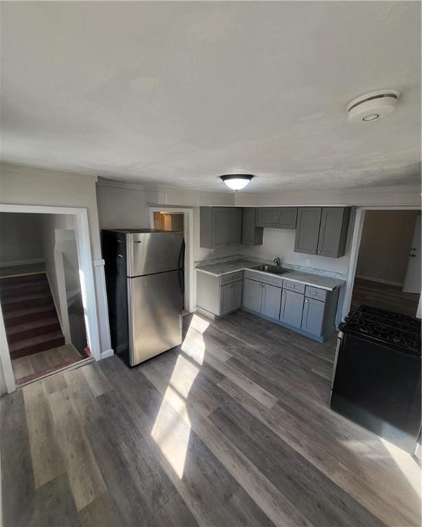 kitchen featuring dark hardwood / wood-style flooring, gray cabinetry, sink, stainless steel refrigerator, and black / electric stove