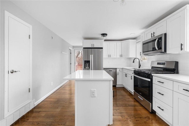 kitchen with dark wood-type flooring, tasteful backsplash, a kitchen island, white cabinetry, and stainless steel appliances