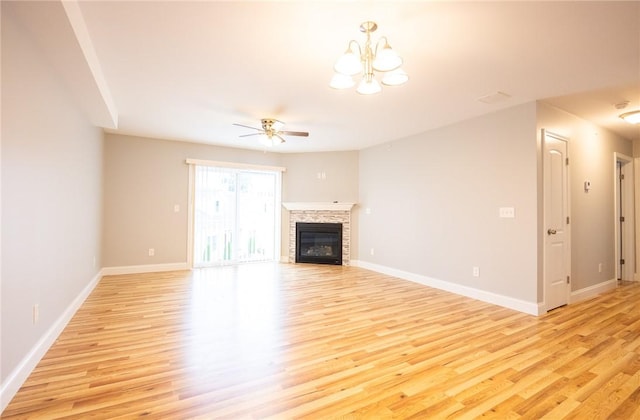 unfurnished living room featuring a fireplace, ceiling fan with notable chandelier, and light wood-type flooring