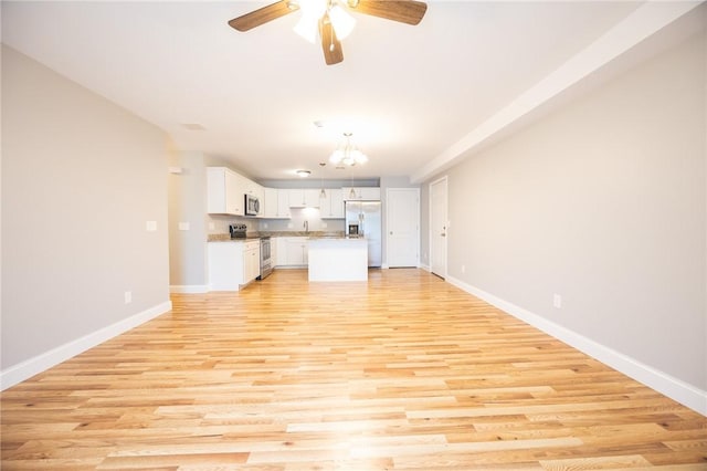 unfurnished living room featuring ceiling fan with notable chandelier, light wood-type flooring, and sink