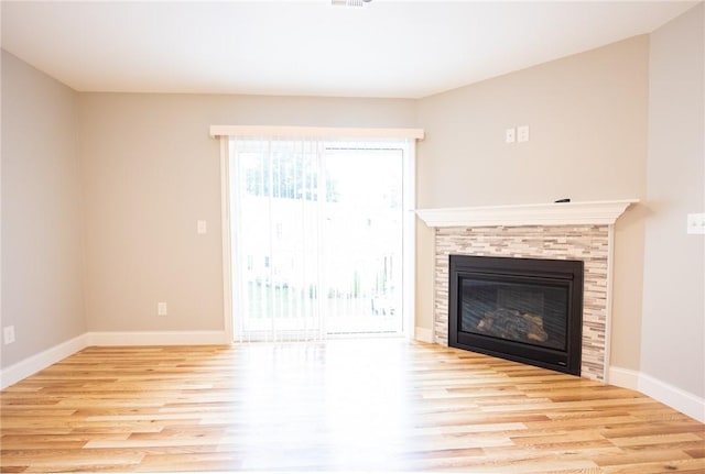 unfurnished living room featuring a tiled fireplace and light hardwood / wood-style flooring