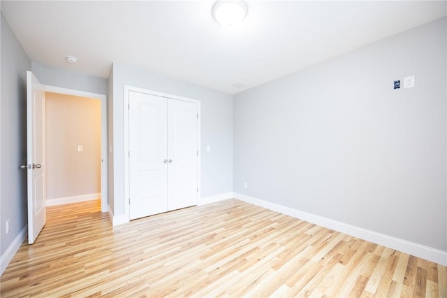 unfurnished bedroom with light wood-type flooring and a closet