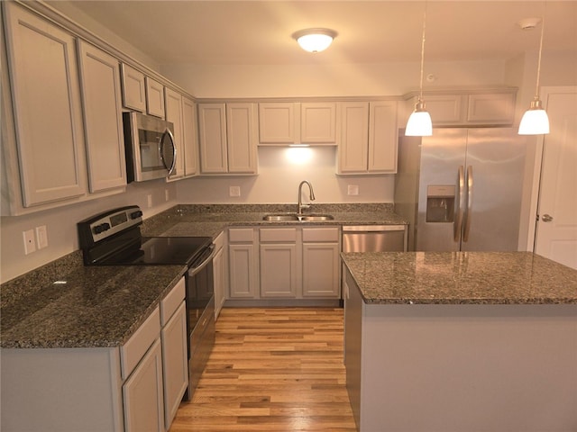 kitchen featuring gray cabinetry, sink, hanging light fixtures, stainless steel appliances, and light wood-type flooring