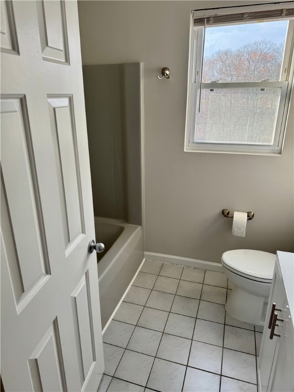 bathroom featuring toilet, vanity, a tub to relax in, and tile patterned floors