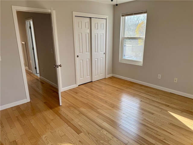 unfurnished bedroom with light wood-type flooring and a closet