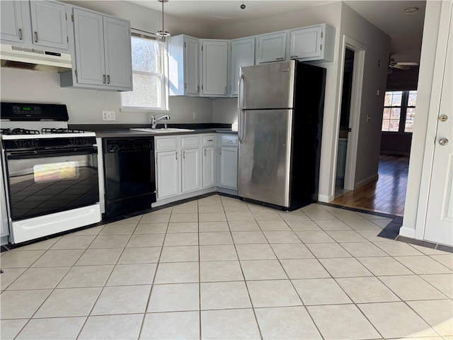 kitchen with white range oven, sink, light tile patterned floors, dishwasher, and stainless steel refrigerator