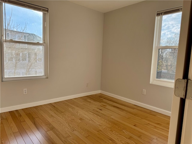 spare room featuring light wood-type flooring and plenty of natural light