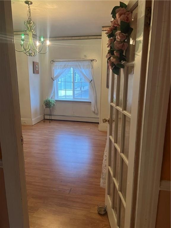 spare room featuring hardwood / wood-style flooring, a notable chandelier, and a baseboard heating unit