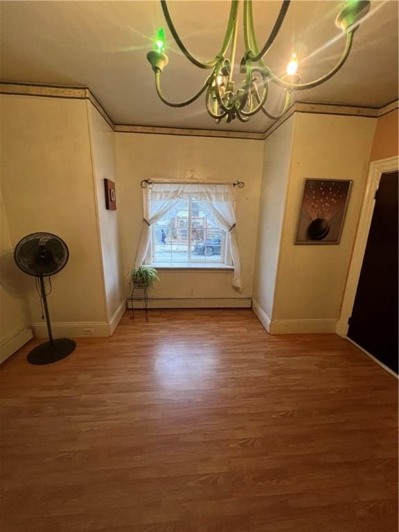 unfurnished dining area with hardwood / wood-style floors, a notable chandelier, ornamental molding, and a baseboard heating unit