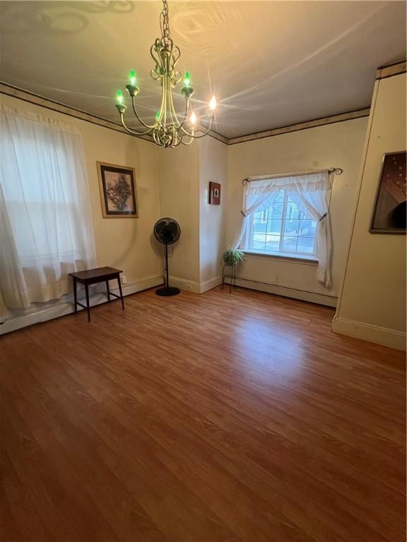 interior space with a notable chandelier, wood-type flooring, and a baseboard radiator