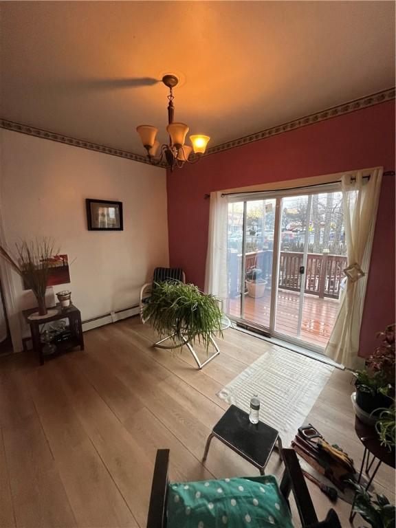 living area with hardwood / wood-style flooring, a baseboard radiator, and a chandelier