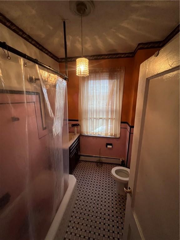 full bathroom with shower / bath combination with curtain, ornamental molding, vanity, baseboard heating, and toilet