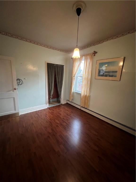 unfurnished room featuring a baseboard heating unit and hardwood / wood-style flooring