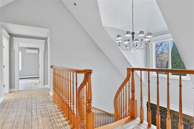 stairway featuring a wall mounted AC, wood-type flooring, a baseboard radiator, and a notable chandelier