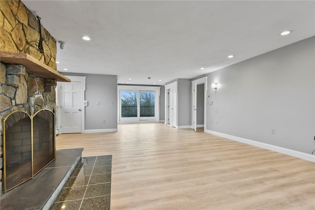 unfurnished living room featuring light hardwood / wood-style flooring and a stone fireplace