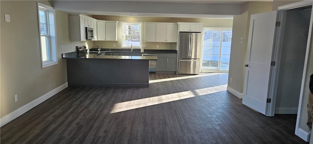 kitchen featuring kitchen peninsula, appliances with stainless steel finishes, sink, dark hardwood / wood-style floors, and white cabinetry