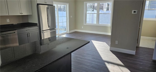 kitchen featuring stainless steel refrigerator, dark hardwood / wood-style flooring, and dark stone countertops