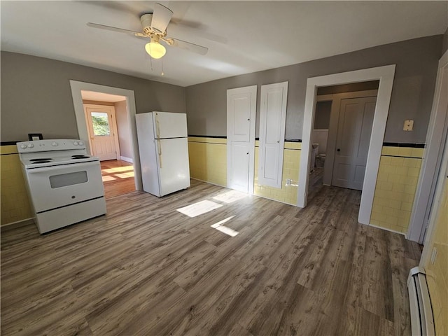 kitchen with white appliances, a baseboard heating unit, ceiling fan, tile walls, and light hardwood / wood-style floors