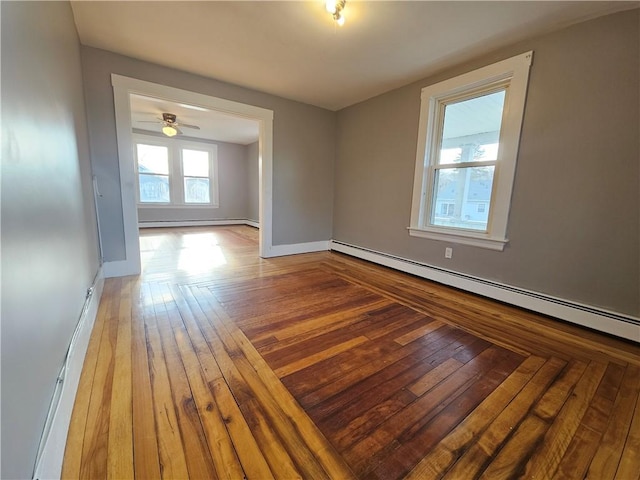 empty room with ceiling fan, wood-type flooring, and baseboard heating