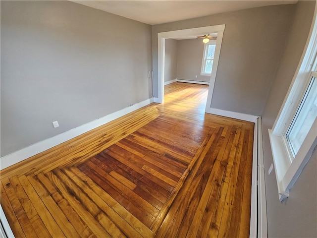 unfurnished room featuring wood-type flooring, ceiling fan, and a baseboard heating unit