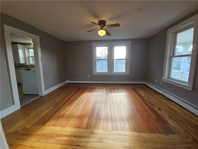 empty room with hardwood / wood-style flooring, ceiling fan, and baseboard heating