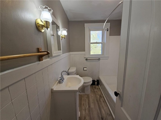 full bathroom featuring vanity, washtub / shower combination, toilet, tile walls, and wood-type flooring