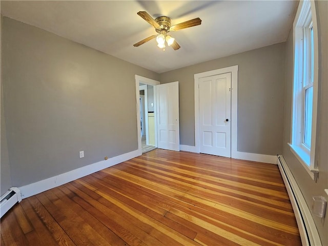 unfurnished bedroom featuring a closet, ceiling fan, a baseboard heating unit, and light hardwood / wood-style floors