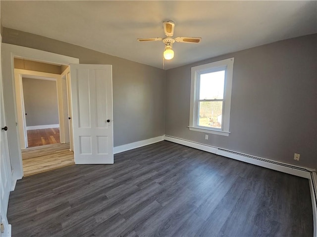 spare room featuring dark hardwood / wood-style floors, ceiling fan, and a baseboard heating unit