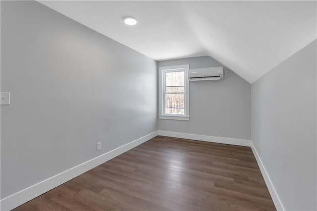 additional living space with a wall mounted air conditioner, dark hardwood / wood-style floors, and vaulted ceiling