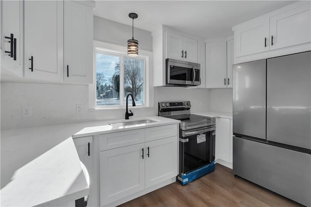 kitchen with sink, hanging light fixtures, stainless steel appliances, dark hardwood / wood-style floors, and white cabinets