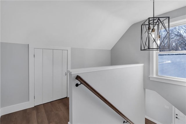 stairway featuring plenty of natural light, wood-type flooring, lofted ceiling, and an inviting chandelier