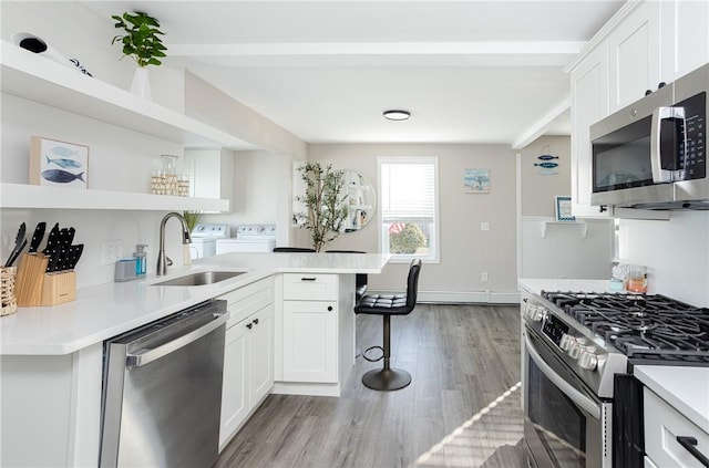 kitchen with white cabinets, sink, independent washer and dryer, and stainless steel appliances